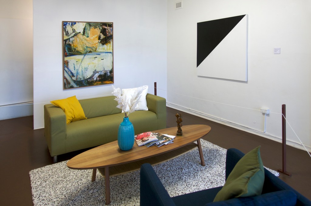 Documentation from the contemporary art installation In the Year Twenty Twenty One by Alex Gawronski held at KNULP gallery in Camperdown, Sydney, Australia. A contemporary art installation in the form of a fictional lounge room setting containing paintings, a sculpture, a vase with colorful artificial flowers and magazines. These are roped off like a museum display.