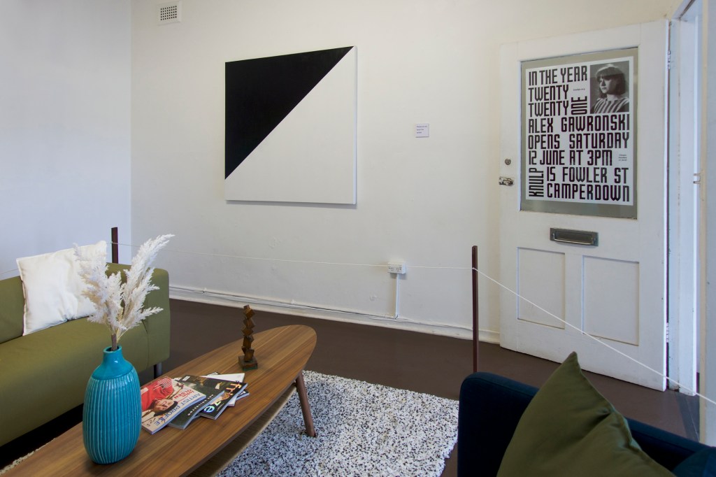 Documentation from the contemporary art installation In the Year Twenty Twenty One by Alex Gawronski held at KNULP gallery in Camperdown, Sydney, Australia. A contemporary art installation in the form of a fictional lounge room setting containing paintings, a sculpture, a vase with colorful artificial flowers and contemporary art magazines. These are roped off like a museum display.